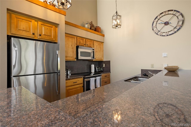 22300 US Highway 6 Unit 1746, Dillon, CO 80435 - kitchen with stainless steel appliances, backsplash, brown cabinetry, a peninsula, and pendant lighting