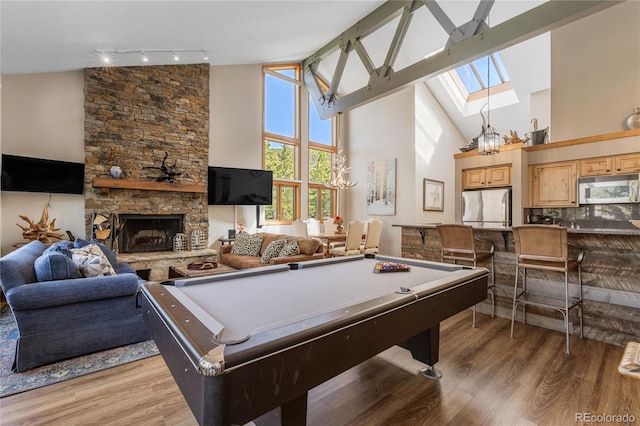 22300 US Highway 6 Unit 1746, Dillon, CO 80435 - recreation room with high vaulted ceiling, light wood finished floors, a skylight, a stone fireplace, and rail lighting