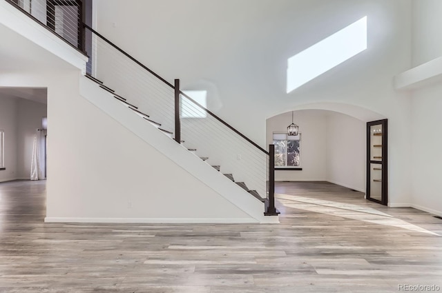 interior space featuring a notable chandelier, light hardwood / wood-style floors, and a towering ceiling