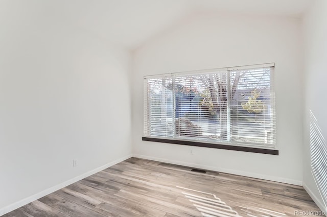 empty room with vaulted ceiling and light hardwood / wood-style flooring