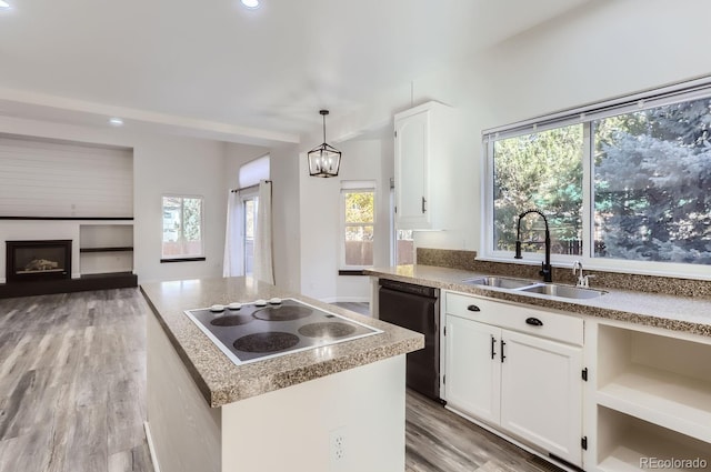 kitchen with electric stovetop, a kitchen island, white cabinetry, black dishwasher, and sink