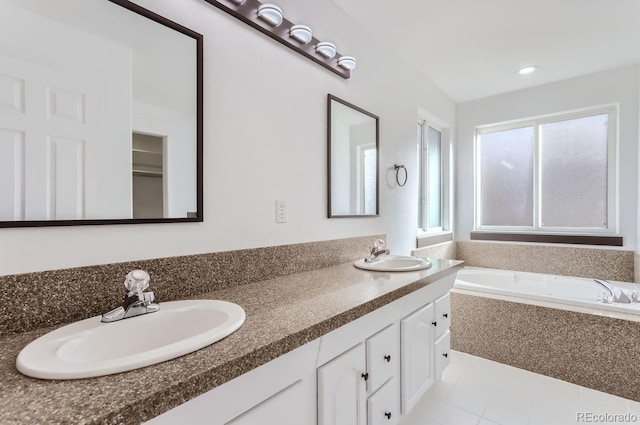 bathroom with vanity, tiled bath, and tile patterned flooring