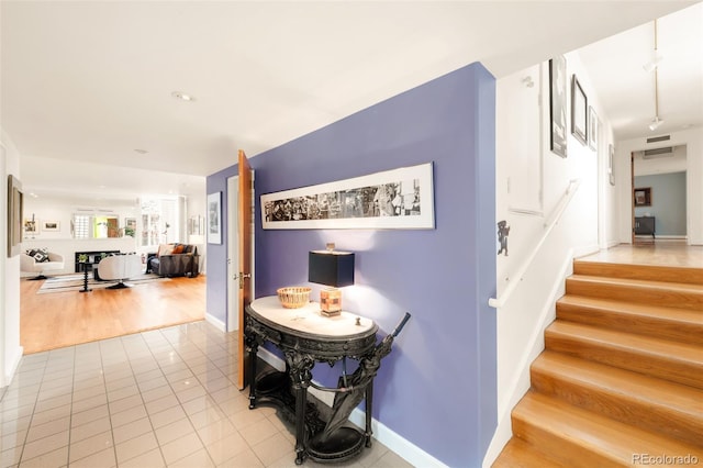 hall with light tile patterned floors, baseboards, and stairs