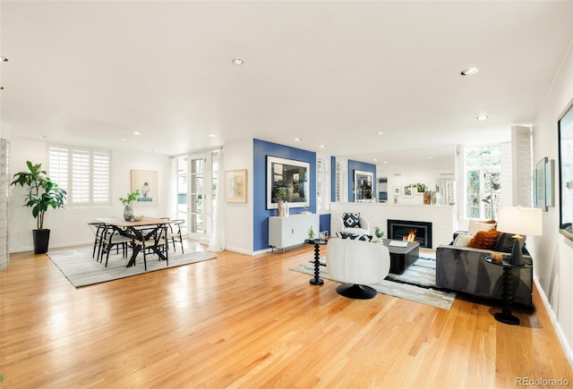 living room featuring recessed lighting, a fireplace, baseboards, and light wood finished floors