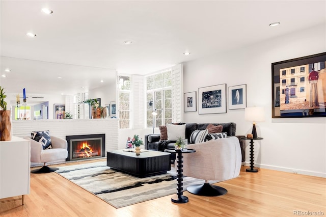 living room featuring recessed lighting, a brick fireplace, baseboards, and wood finished floors