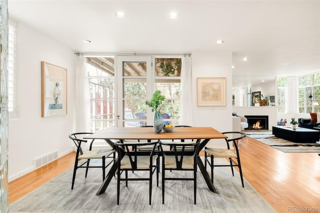 dining room with recessed lighting, visible vents, light wood-style floors, and a brick fireplace