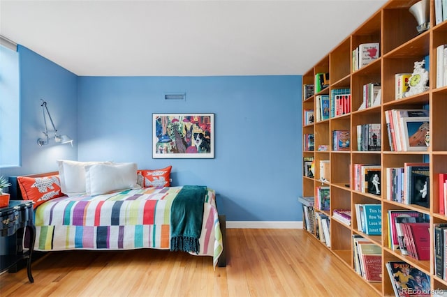 bedroom with wood finished floors, visible vents, and baseboards