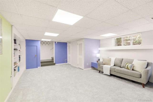 living area with stairs, a paneled ceiling, baseboards, and carpet flooring