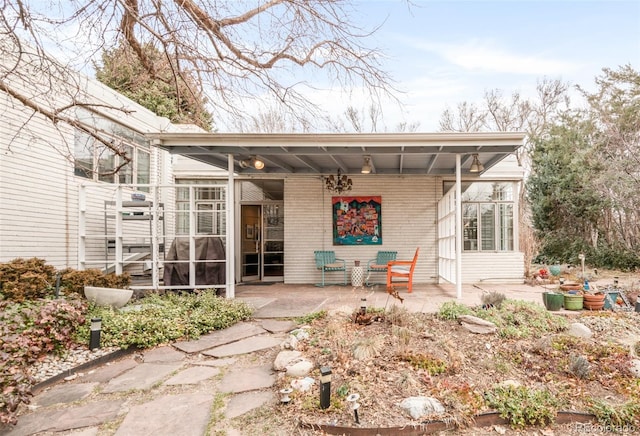 rear view of property with brick siding, a patio, and a sunroom