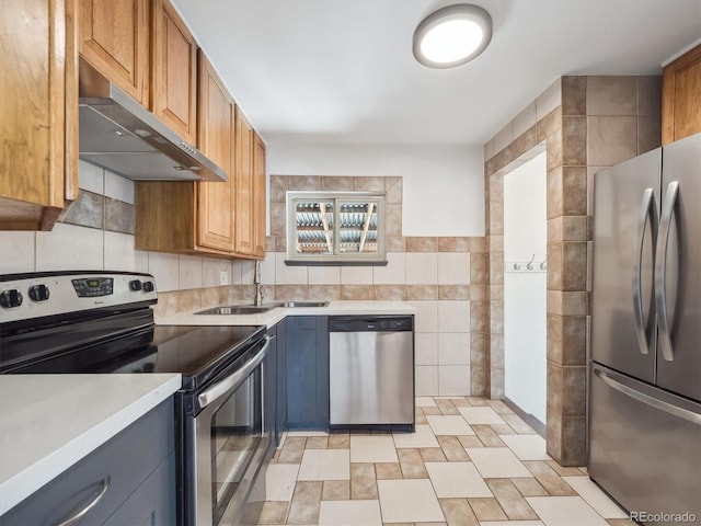 3050 S Delaware St, Englewood, CO 80110 - kitchen featuring appliances with stainless steel finishes, tile walls, under cabinet range hood, light countertops, and brown cabinets