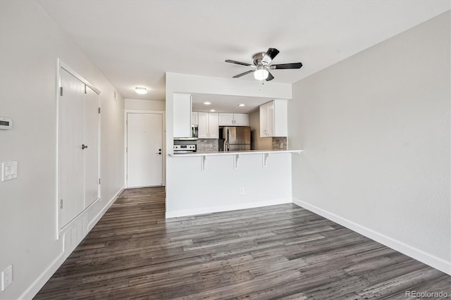 4273 S Salida Way Unit 1, Aurora, CO 80013 - kitchen with stainless steel appliances, a ceiling fan, white cabinetry, a breakfast bar area, and dark wood-style floors