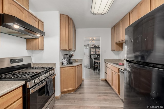 kitchen featuring light countertops, light wood finished floors, under cabinet range hood, and stainless steel appliances