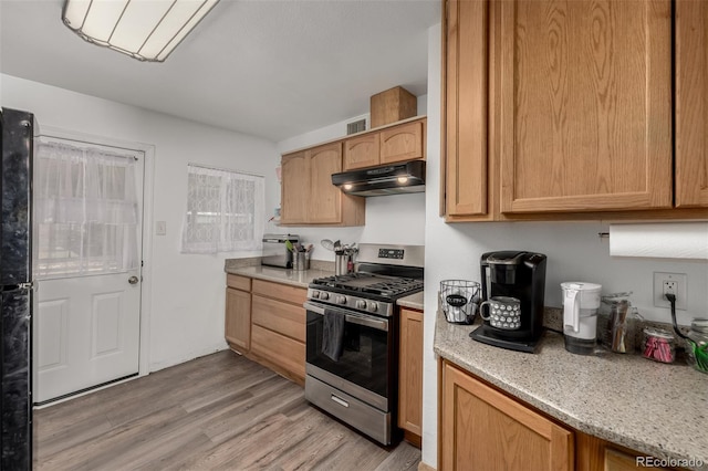 kitchen featuring under cabinet range hood, visible vents, stainless steel range with gas cooktop, and light wood finished floors