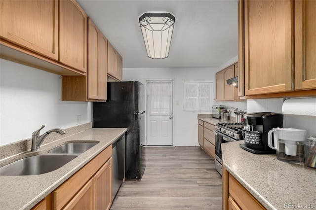 kitchen featuring stainless steel appliances, light wood-type flooring, light countertops, and a sink