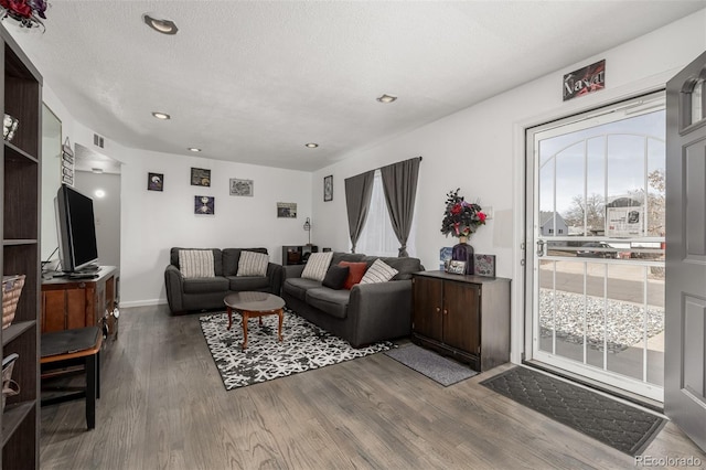 living room featuring visible vents, a healthy amount of sunlight, a textured ceiling, and wood finished floors