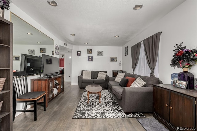 living area featuring visible vents, a textured ceiling, and wood finished floors