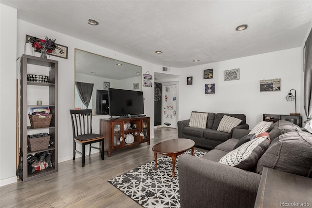 living area with recessed lighting, visible vents, baseboards, and wood finished floors