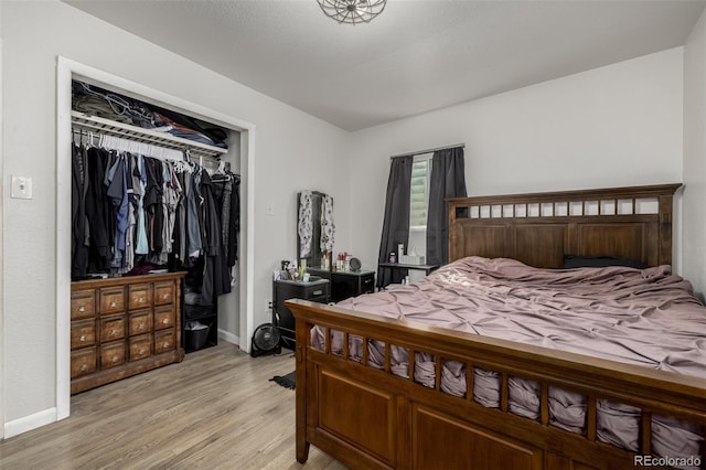 bedroom with a closet, baseboards, and light wood-style flooring