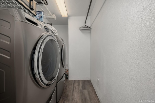 laundry room with laundry area, washer and dryer, a textured wall, and dark wood-style flooring