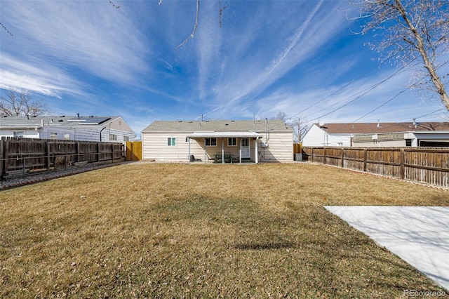 back of property with a fenced backyard, entry steps, and a yard