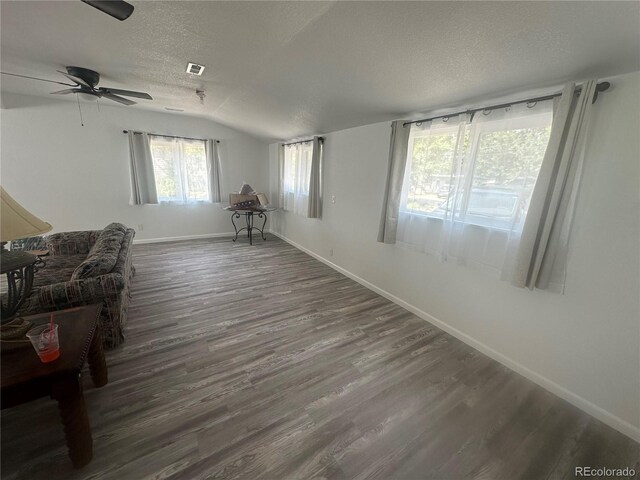 living room featuring visible vents, baseboards, lofted ceiling, wood finished floors, and a textured ceiling