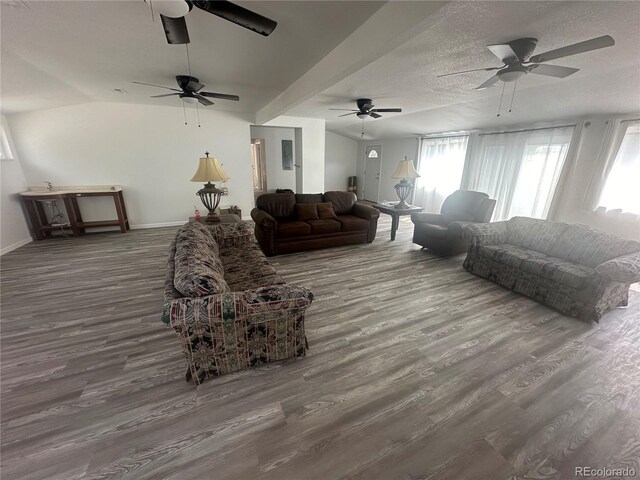 living area with baseboards, lofted ceiling, a textured ceiling, and wood finished floors