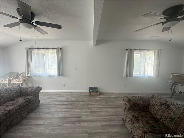 living area with baseboards, a textured ceiling, lofted ceiling, and wood finished floors