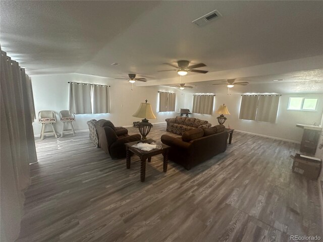 living area with visible vents, baseboards, dark wood-type flooring, and lofted ceiling