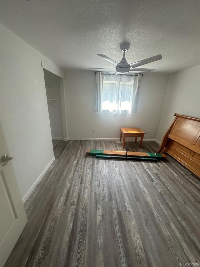 unfurnished bedroom featuring ceiling fan, wood finished floors, baseboards, and a textured ceiling