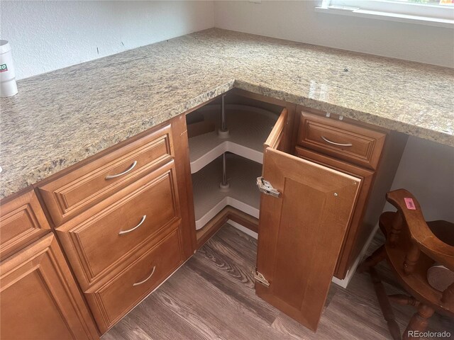 details featuring light stone counters, brown cabinets, dark wood-style floors, and built in desk