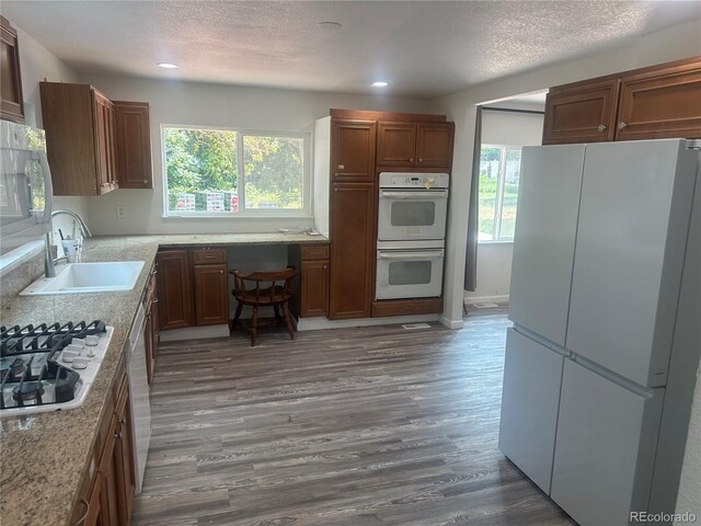 kitchen featuring a textured ceiling, white appliances, dark wood-type flooring, and a sink