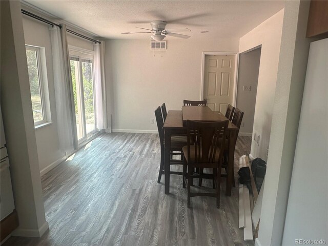 dining space with visible vents, a textured ceiling, wood finished floors, baseboards, and ceiling fan