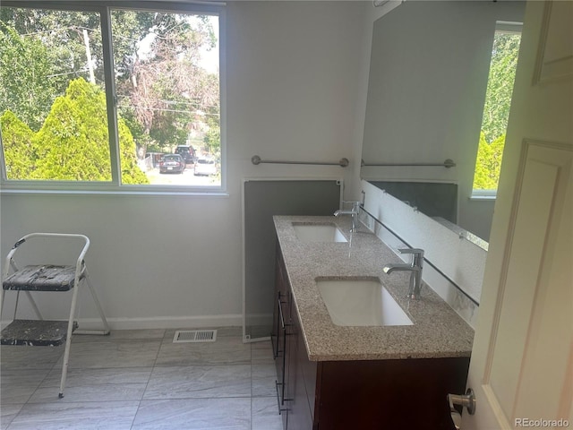 bathroom with double vanity, visible vents, baseboards, and a sink