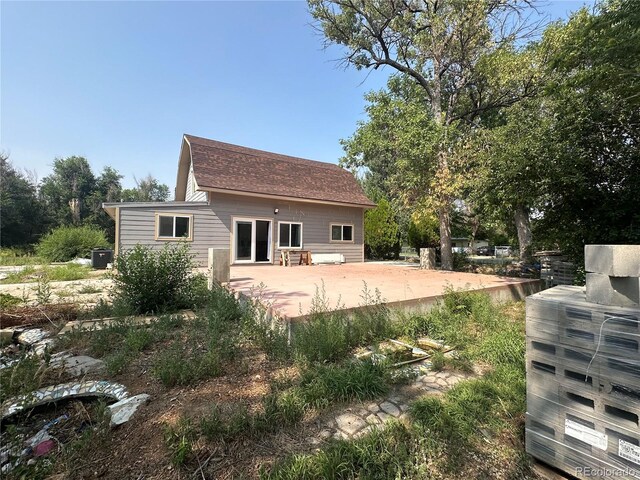 back of property with a patio area and roof with shingles