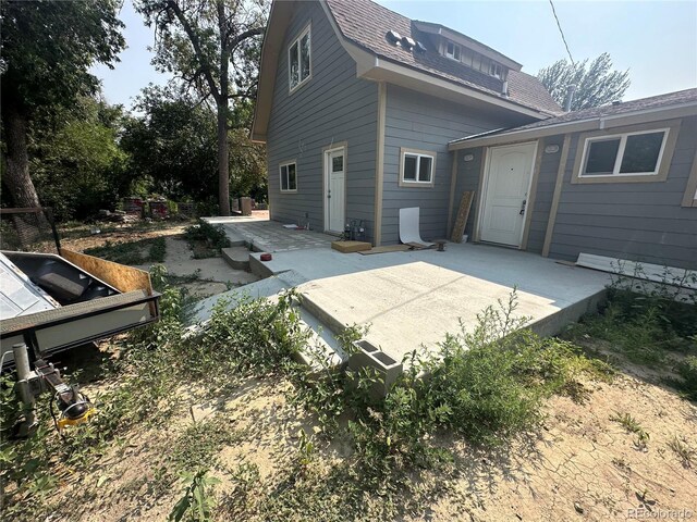 back of property with a patio area and roof with shingles