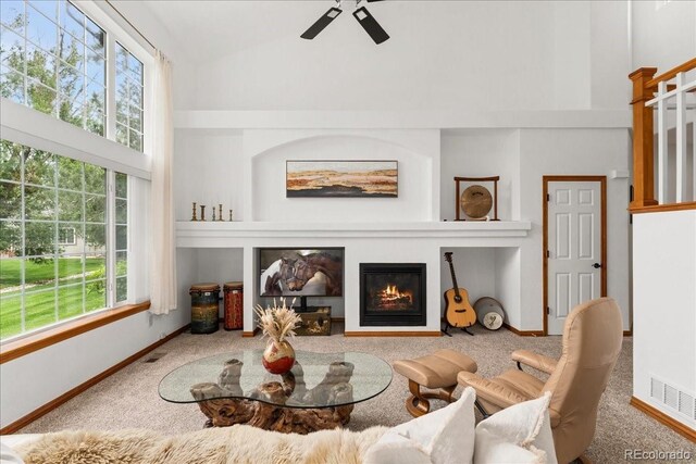 11705 W Stanford Ln, Morrison, CO 80465 - living room with high vaulted ceiling, carpet flooring, plenty of natural light, a glass covered fireplace, and a ceiling fan
