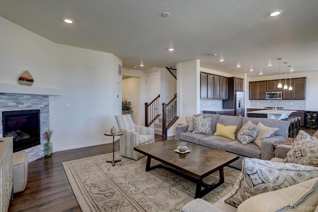 living room with sink, a fireplace, and dark hardwood / wood-style floors