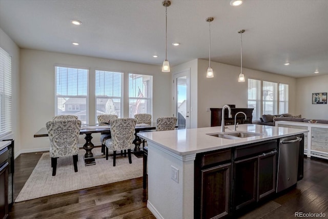 kitchen with pendant lighting, sink, dark wood-type flooring, dishwasher, and an island with sink