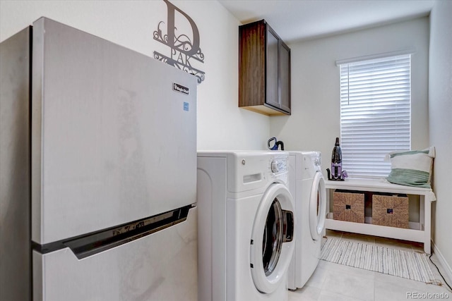 laundry area featuring separate washer and dryer, cabinets, and light tile patterned flooring