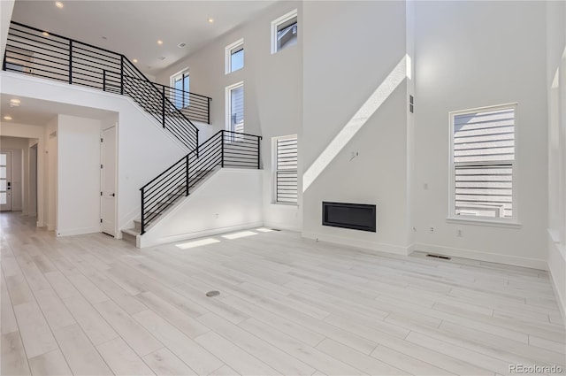 unfurnished living room with light hardwood / wood-style flooring and a high ceiling