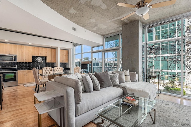 living room featuring floor to ceiling windows, light hardwood / wood-style flooring, and ceiling fan