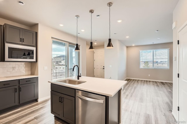 kitchen with pendant lighting, dishwasher, sink, decorative backsplash, and built in microwave