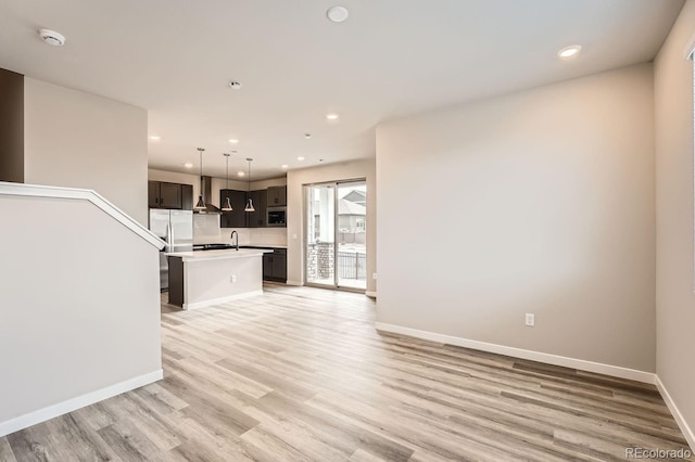 unfurnished living room featuring sink and light hardwood / wood-style floors