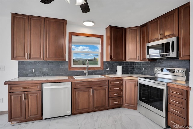 906 Central, Kremmling, CO 80459 - kitchen featuring appliances with stainless steel finishes, ceiling fan, tasteful backsplash, light marble finish flooring, and tile counters