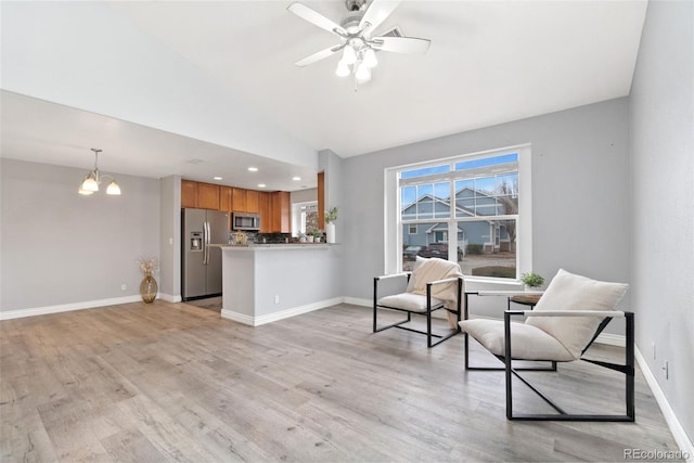 sitting room with ceiling fan with notable chandelier, light hardwood / wood-style floors, and vaulted ceiling