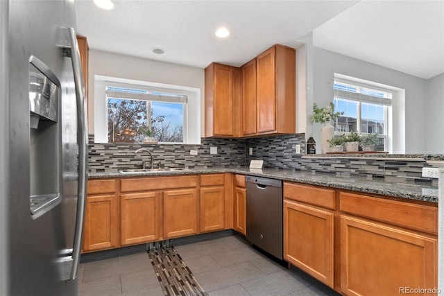 kitchen featuring tasteful backsplash, appliances with stainless steel finishes, sink, and dark stone counters