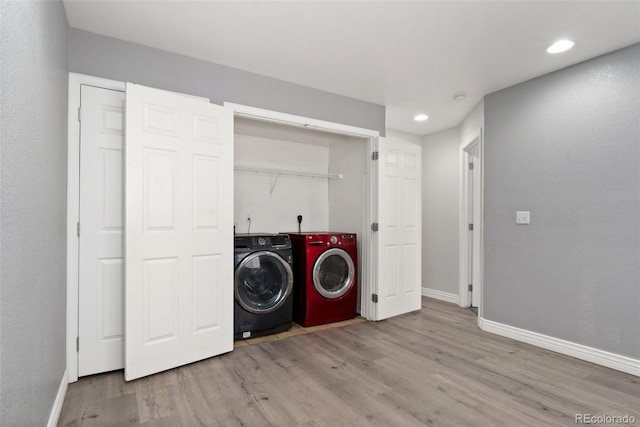 laundry area with light hardwood / wood-style flooring and washing machine and dryer