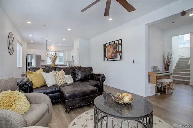 living area featuring stairway, light wood-type flooring, and a wealth of natural light