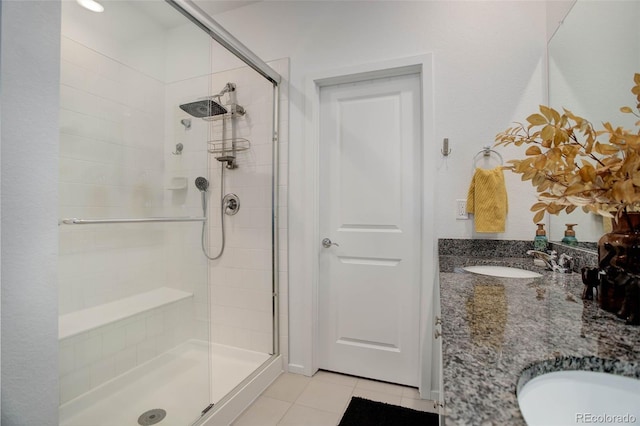 bathroom featuring a stall shower, tile patterned flooring, a sink, and double vanity