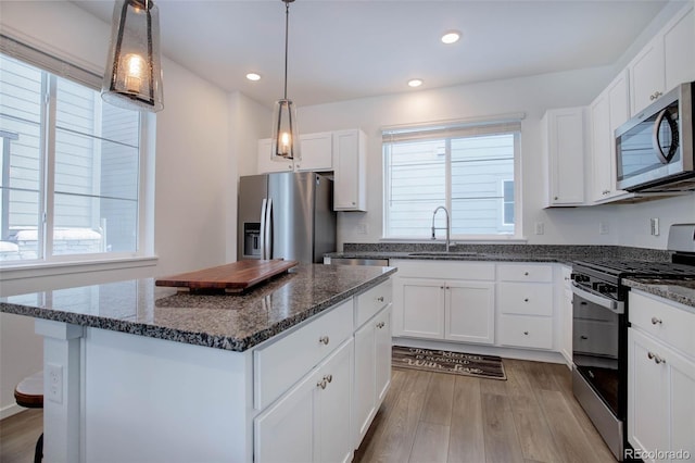 kitchen with appliances with stainless steel finishes, white cabinetry, a sink, and light wood-style flooring